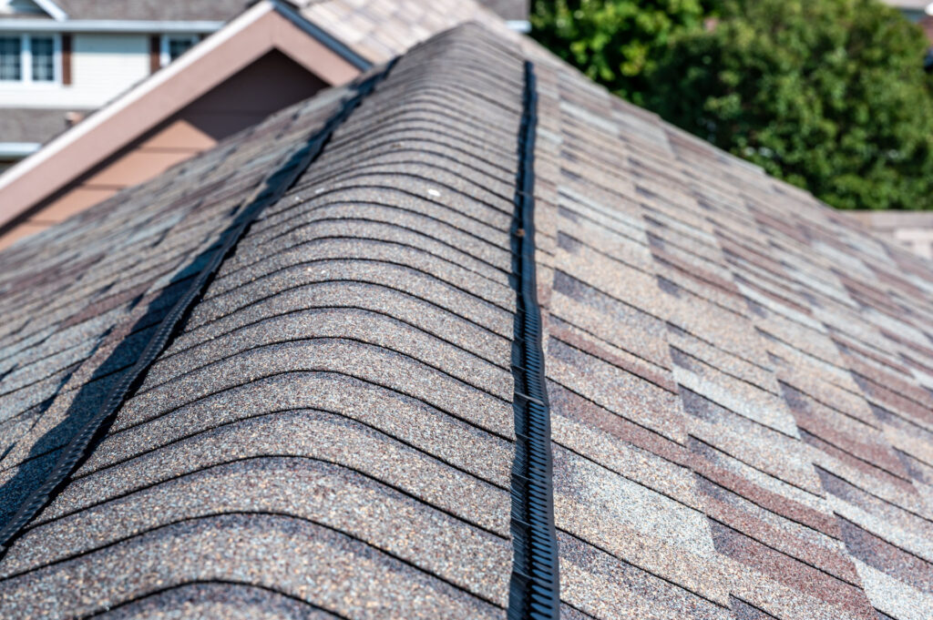 Ridge cap vent installed on a shingle roof for passive attic ventilation on a residential house